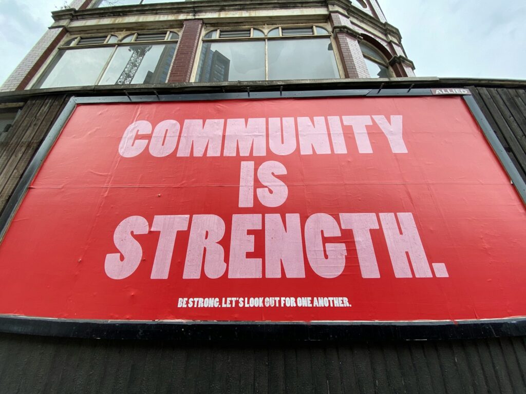 red and white sign with words that say community is strength