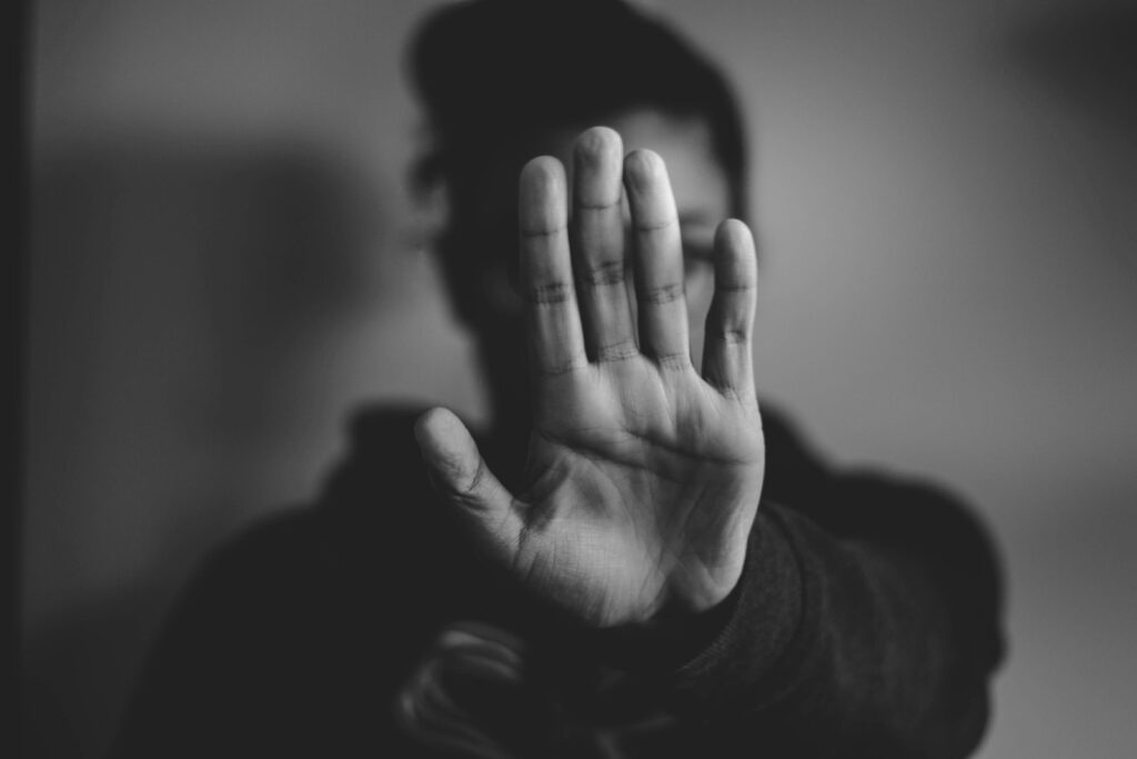 close-up photography of person lifting hands to hide his identity