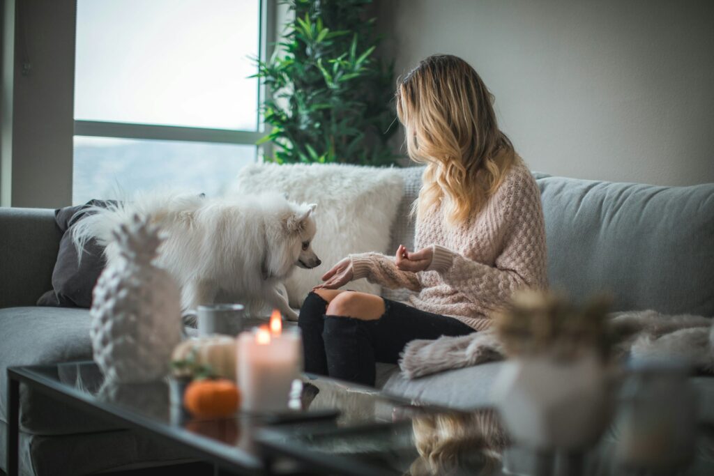 woman, a ministays guest, sitting on sofa while holding food for dog