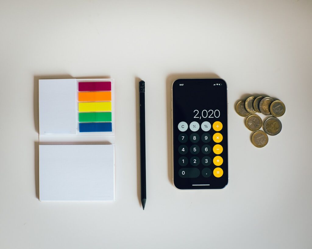 black iphone 12 in the calculator function next to a paper pad and pen 