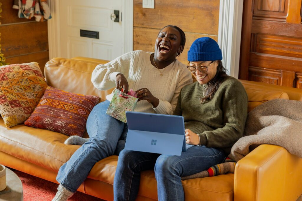 two friends sitting on a couch with a laptop making a ministays profile