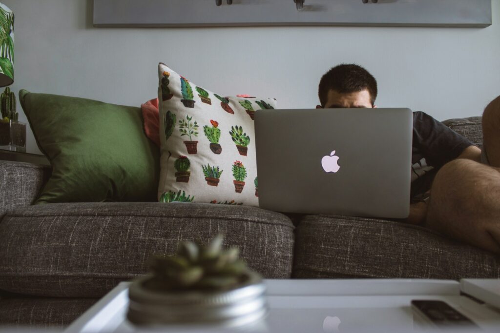 man sitting on sofa using MacBook to find MiniStays rebook and refund policy